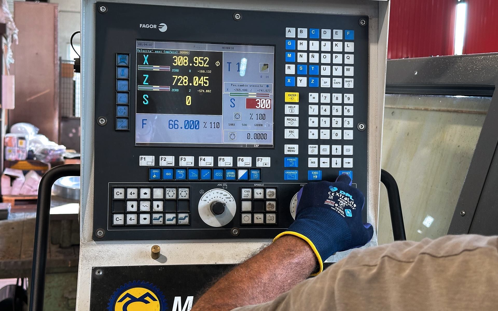 Mano con guanto sul pannello di controllo di una macchina CNC